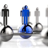 A blue human figurine stands out from a group of gray figurines, symbolizing leadership or uniqueness.