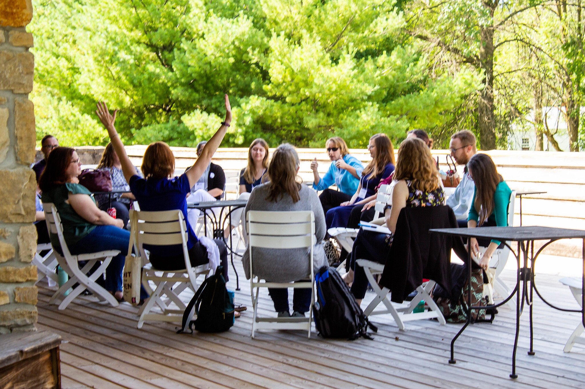 Group of people sitting outside on a deck, having a conversation.