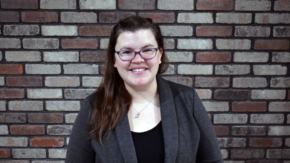 Pictured is Andrea Bearman in front of a brick wall smiling