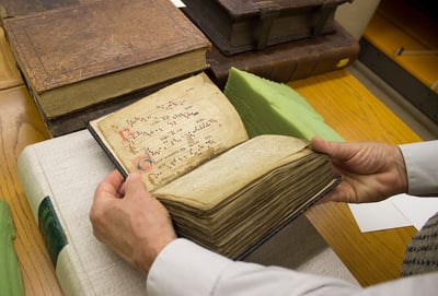 Pair of hands holding a rare book in Saint Meinrad's archives room