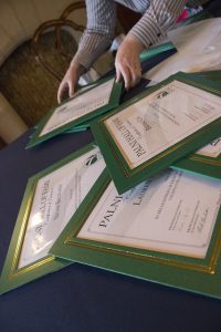 Pile of PALNI Award certificates with pair of hands holding one on the top of the pile