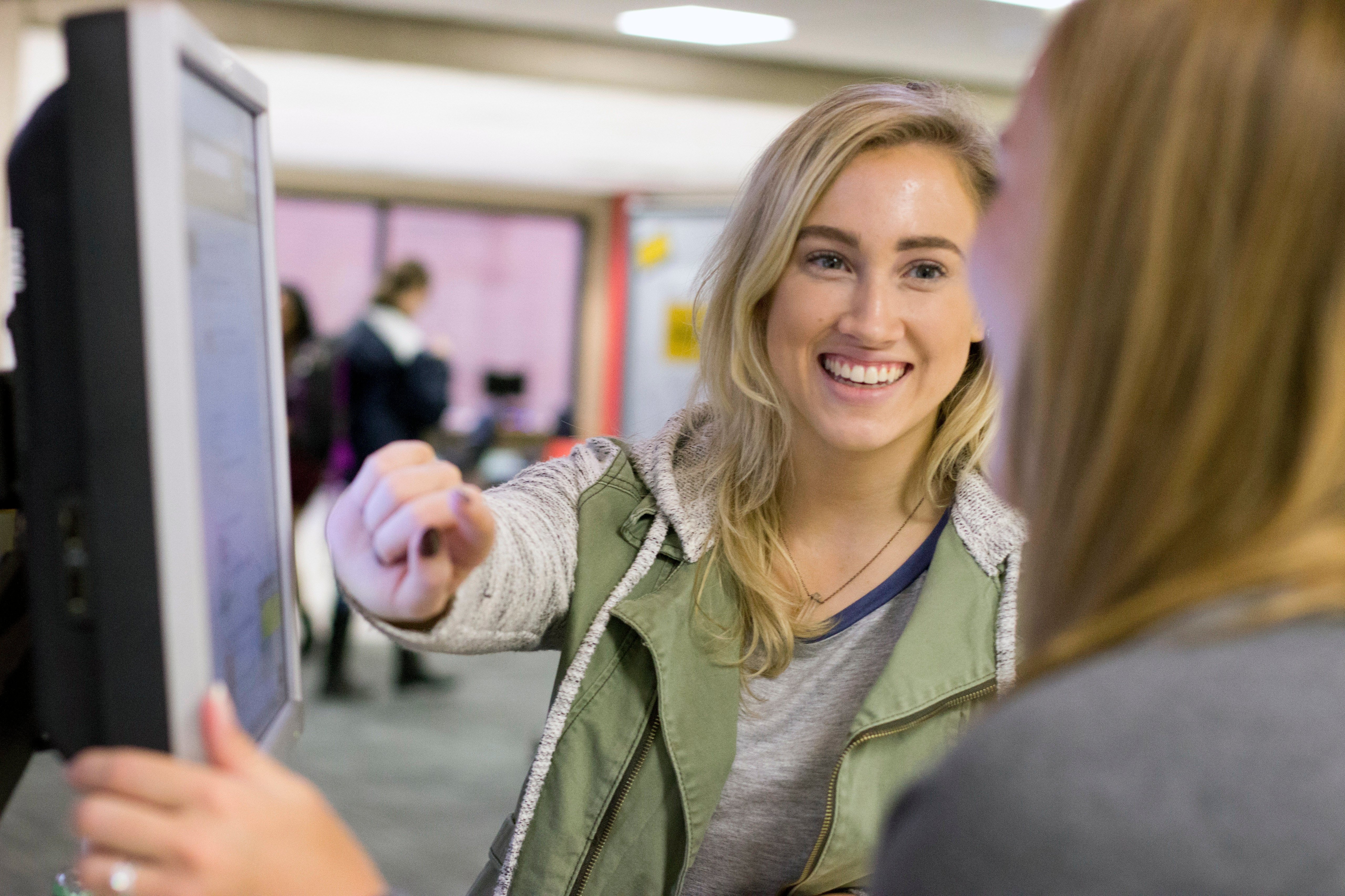 Students smiling and pointing at computer screen Students smiling and pointing at computer screen