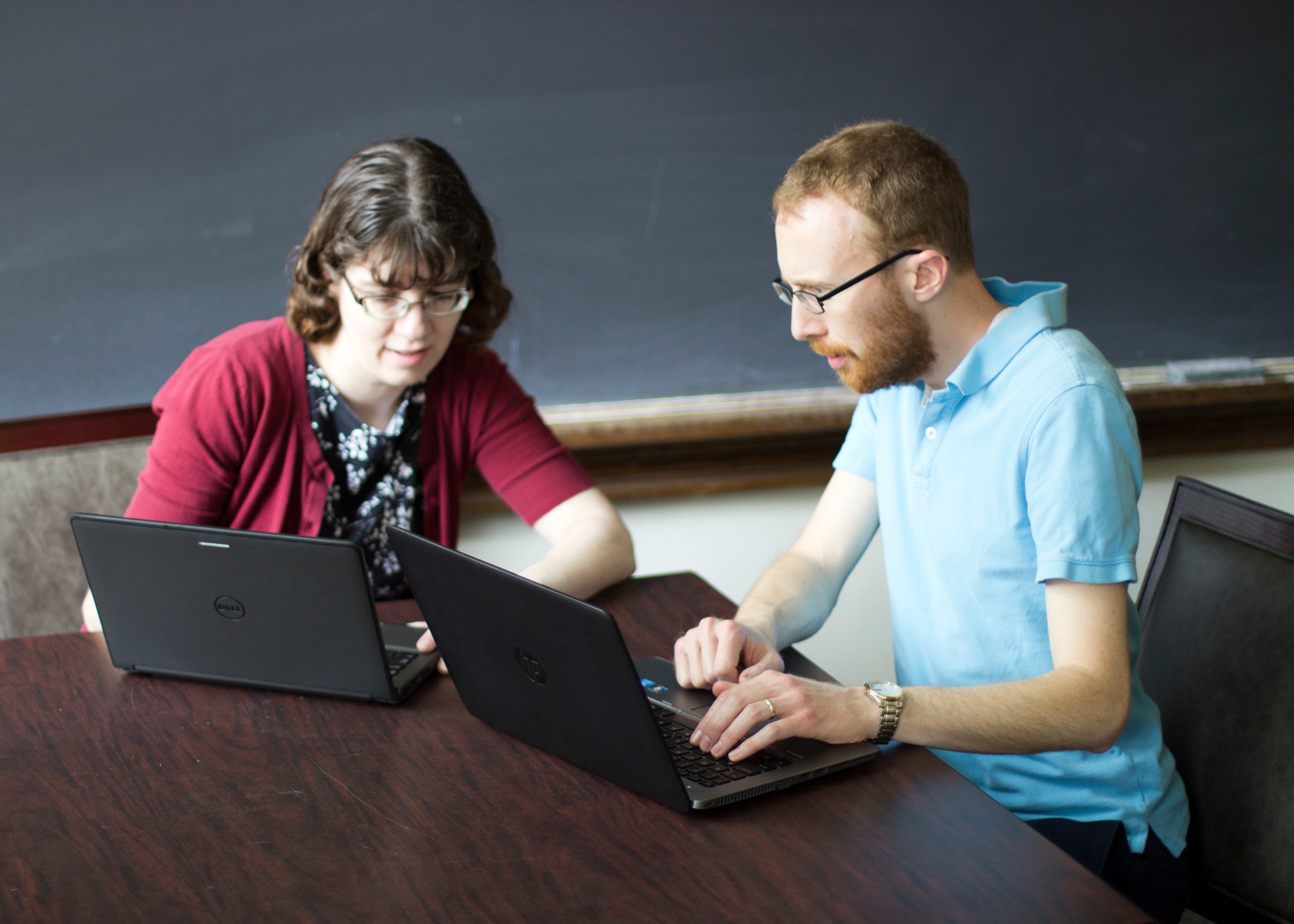 Two PALNI employees sitting at a desk looking at laptops