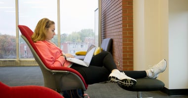 University of Indianapolis student sitting in the library looking at a laptop.