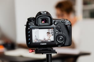 Photo of camera with preview screen showing person sitting at a computer