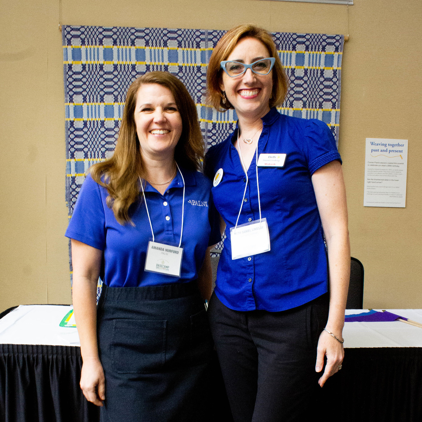Two PALNI people standing together in front of a table and smiling