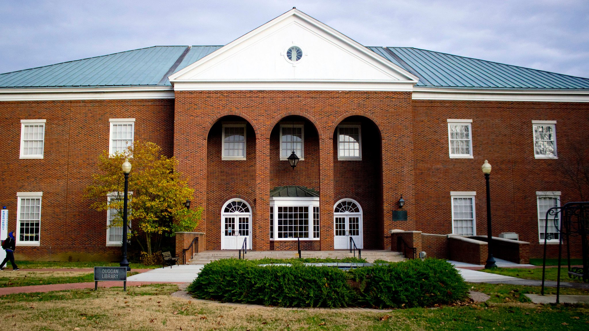 Front of Hanover College brick building with bushes and trees in front