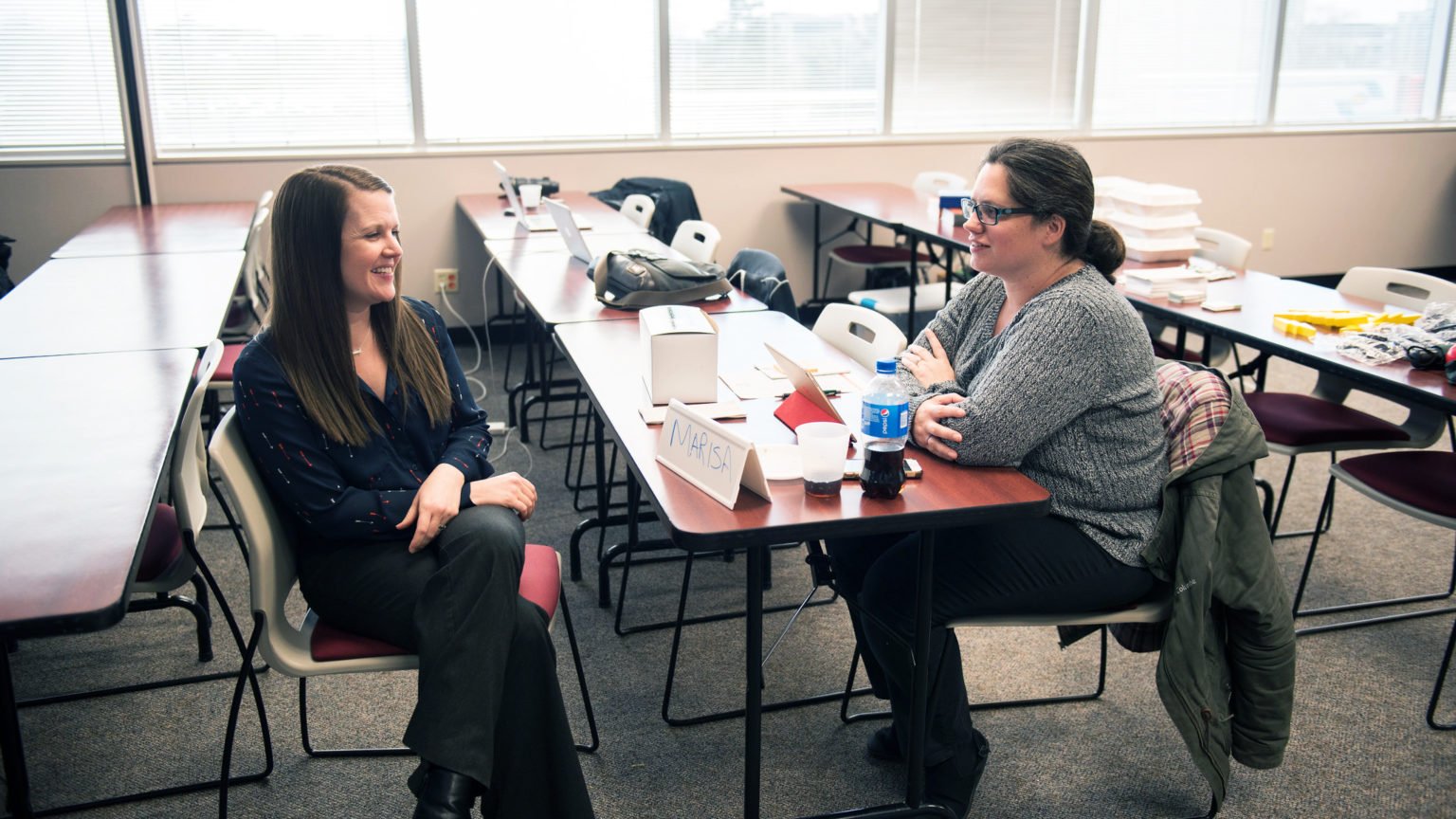Scholarly  Communications Director Amanda Hurford sits across from UIndy Library Director Marisa Albrecht and they are smiling.
