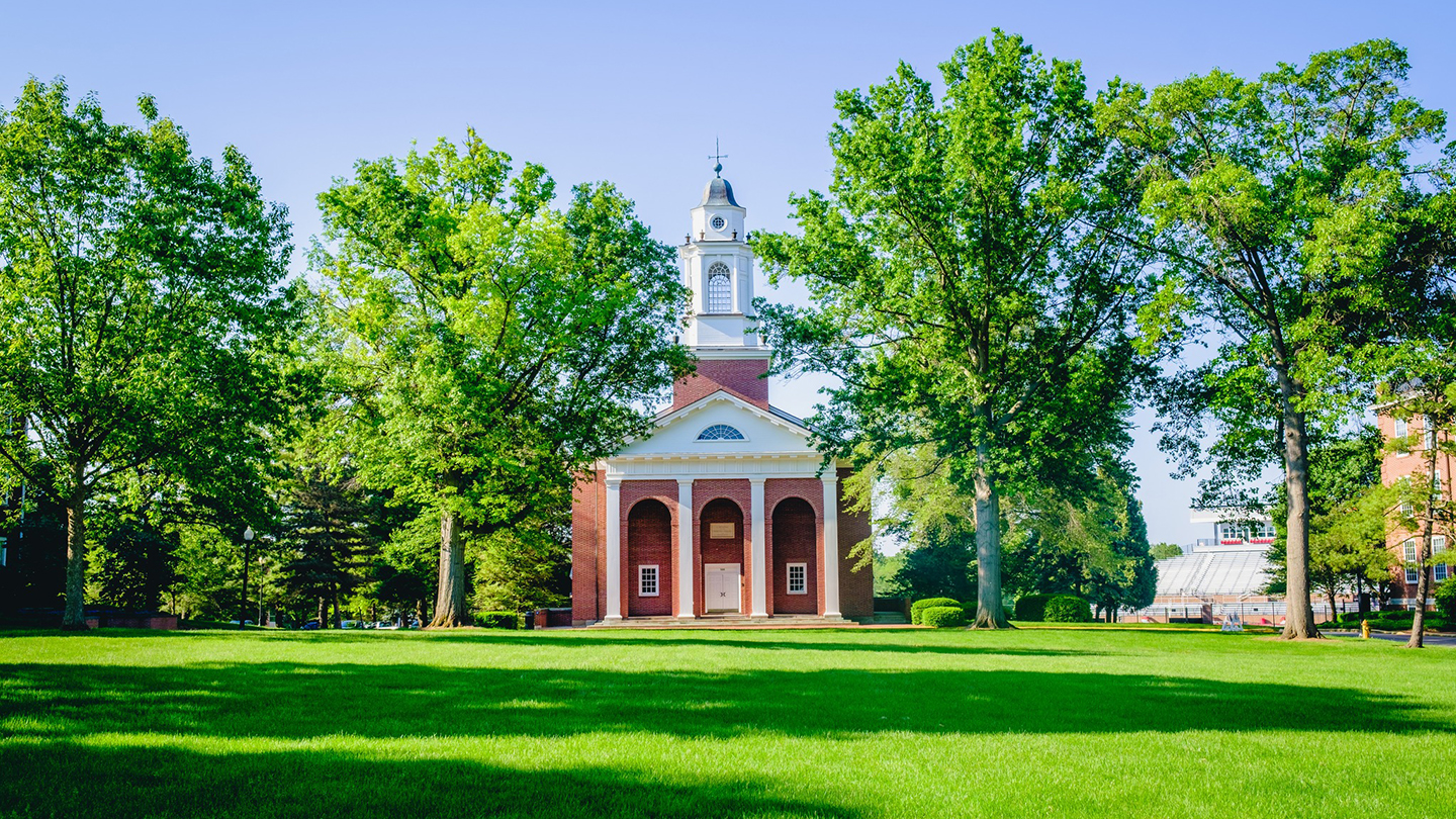 Wabash College brick building with pillars set back in a bunch of trees