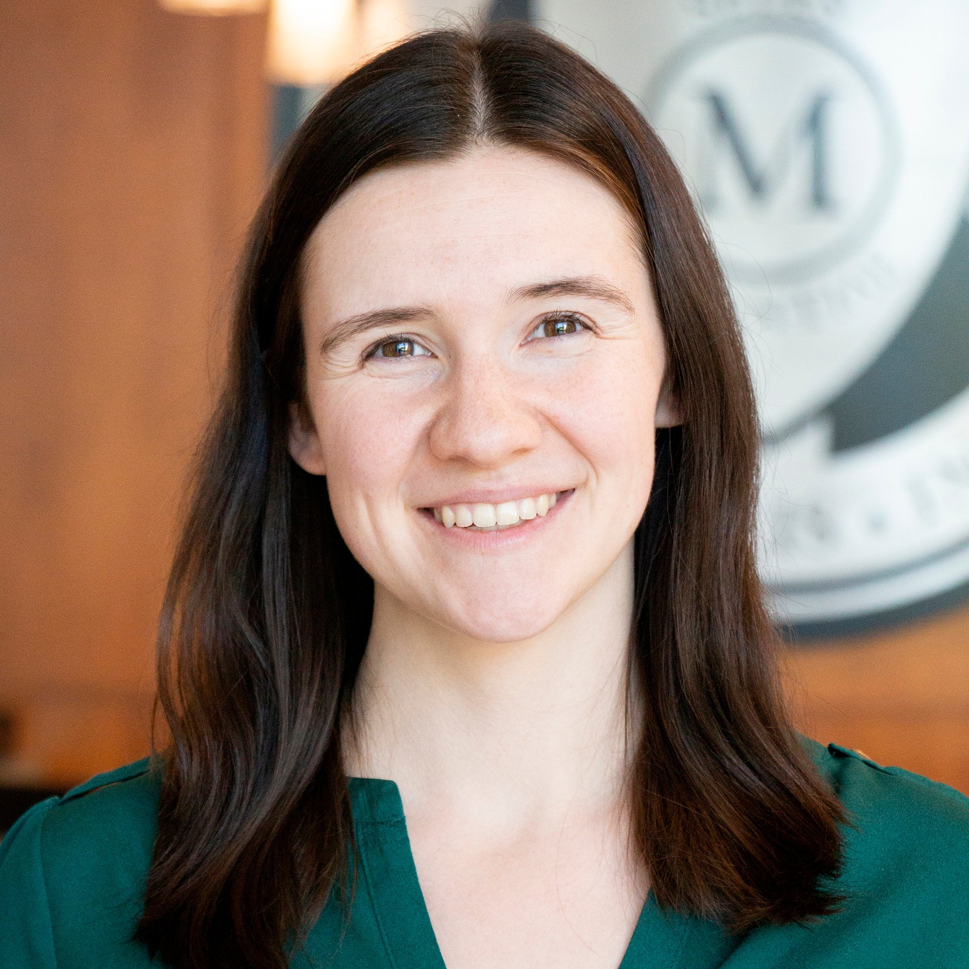 Pictured is Caitlin Balgeman wearing a green shirt with the Marian University logo in the background