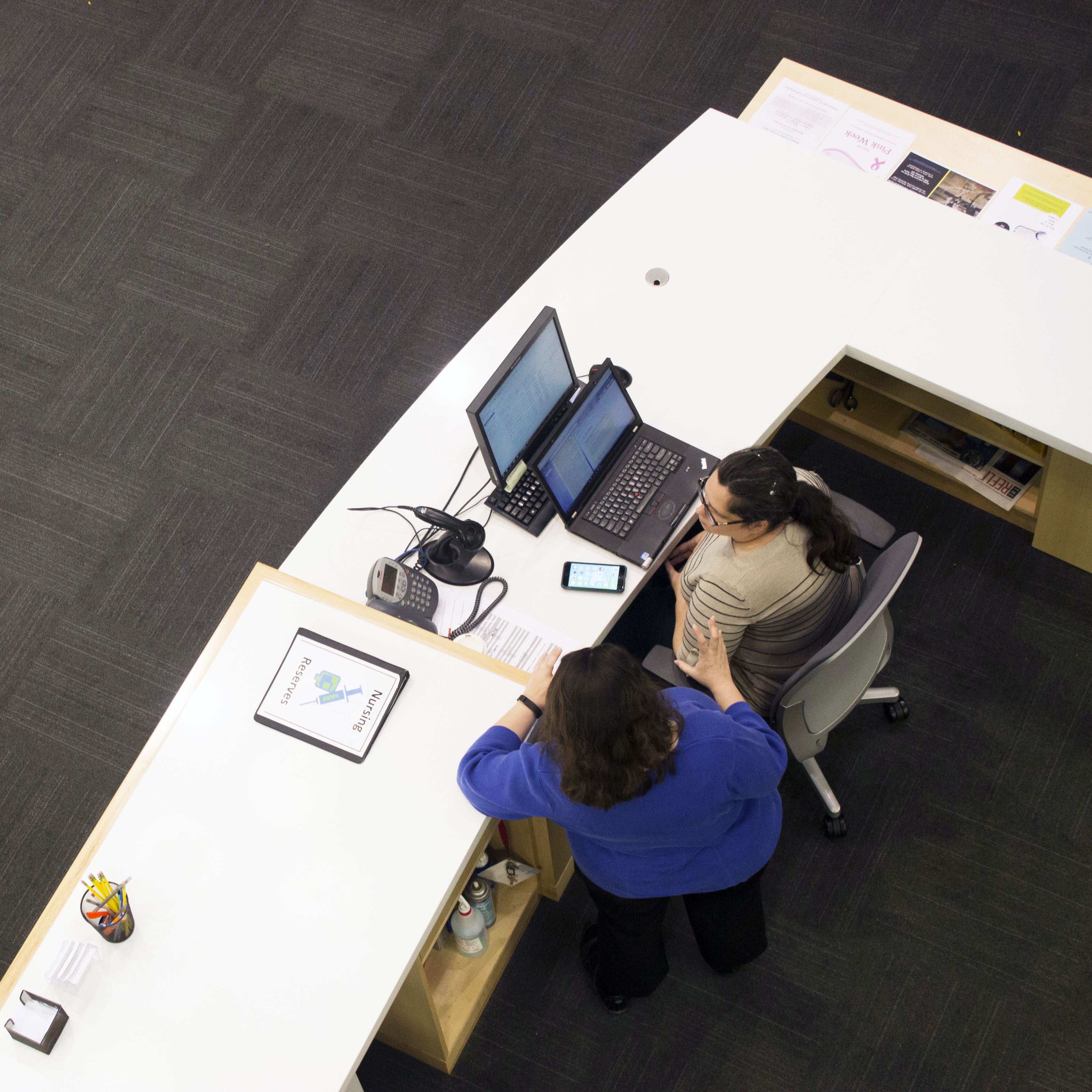 aerial view of two library staff at a reference desk